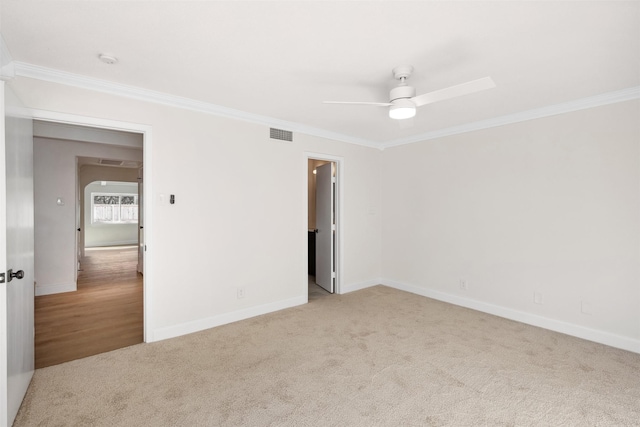 unfurnished room with crown molding, light colored carpet, and ceiling fan