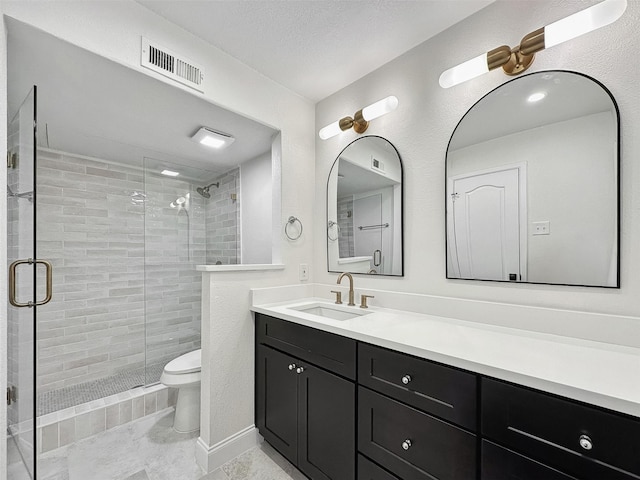 bathroom featuring a shower with door, vanity, a textured ceiling, and toilet