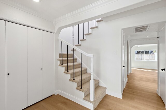 spare room featuring lofted ceiling, crown molding, and light wood-type flooring