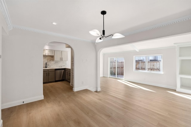 unfurnished living room with ornamental molding, sink, a notable chandelier, and light hardwood / wood-style flooring