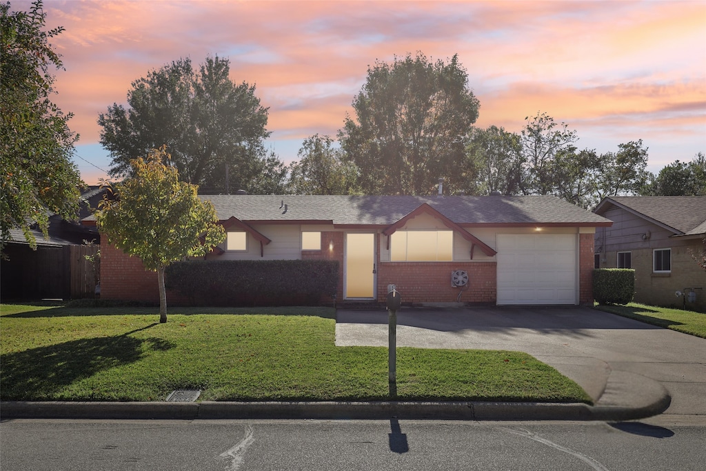 ranch-style home featuring a garage and a lawn