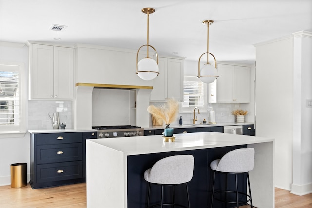 kitchen featuring white cabinetry, hanging light fixtures, sink, and a center island