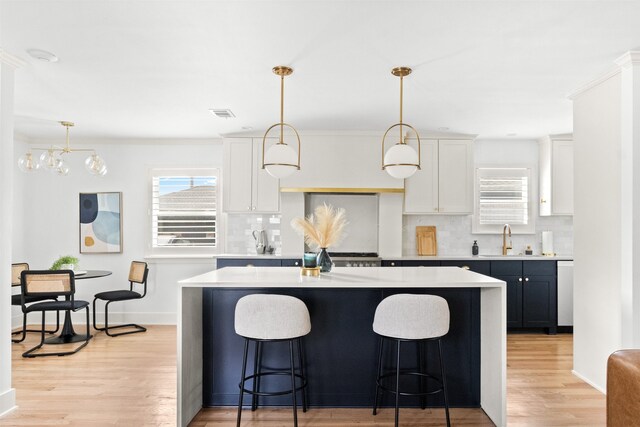 kitchen featuring high end stainless steel range oven, white cabinetry, light hardwood / wood-style floors, decorative light fixtures, and a barn door