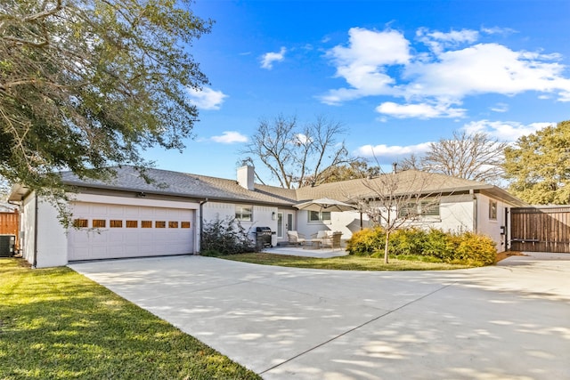 ranch-style home featuring a garage, a front yard, and central air condition unit