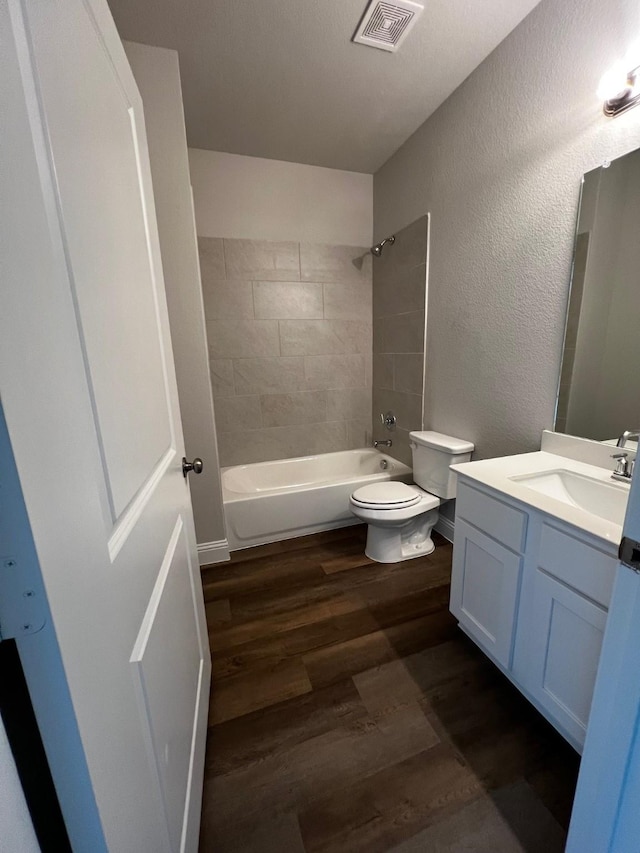 full bathroom with tiled shower / bath combo, wood-type flooring, vanity, and toilet