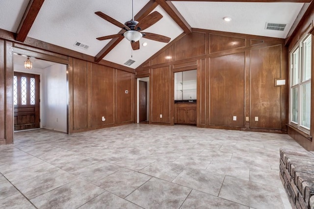 unfurnished living room featuring vaulted ceiling with beams, ceiling fan, and wood walls