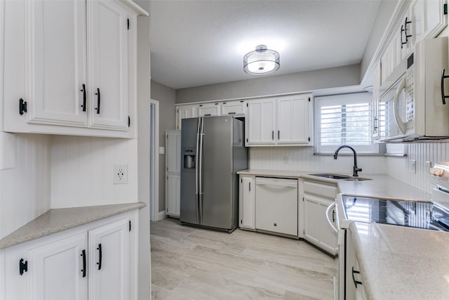 kitchen with sink, white appliances, a textured ceiling, and white cabinets