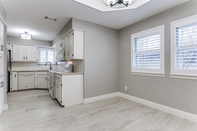 kitchen with white cabinetry, sink, backsplash, and white appliances