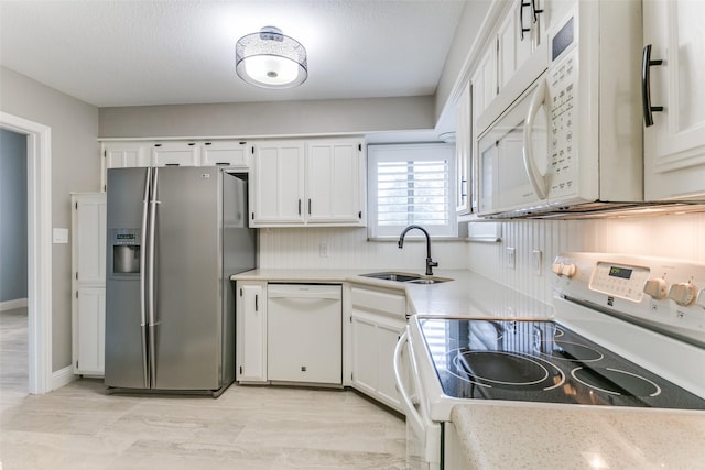 kitchen featuring sink, a textured ceiling, white cabinets, and white appliances