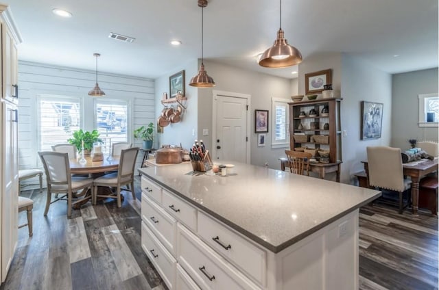 kitchen featuring white cabinetry, a center island, pendant lighting, and dark hardwood / wood-style flooring