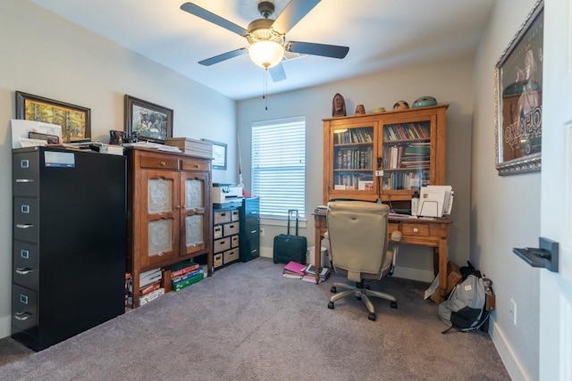 carpeted office space featuring baseboards and ceiling fan