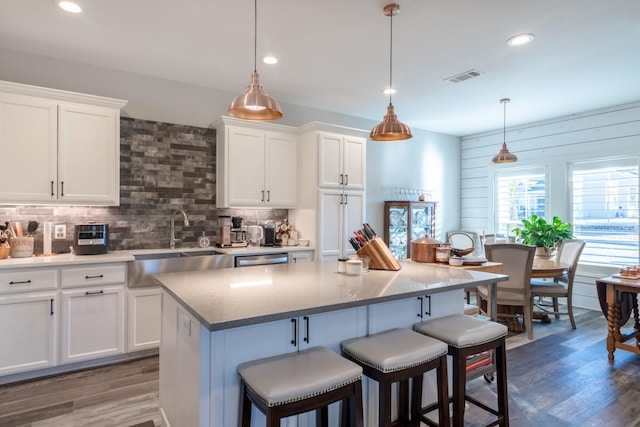 kitchen featuring a kitchen breakfast bar, wood finished floors, visible vents, and a sink