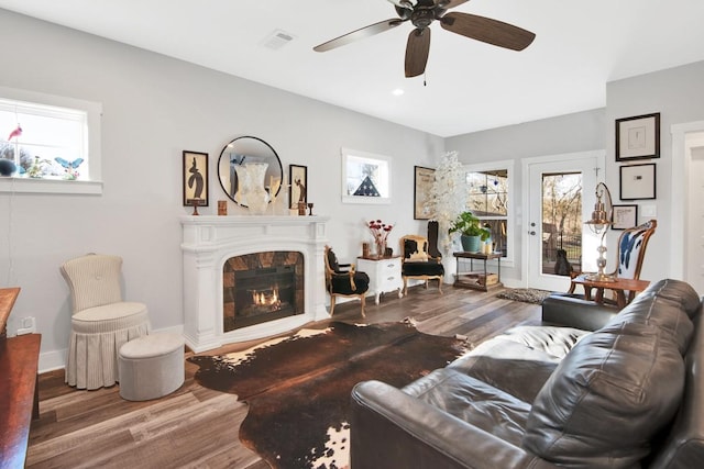 living room with hardwood / wood-style floors, a tile fireplace, and ceiling fan