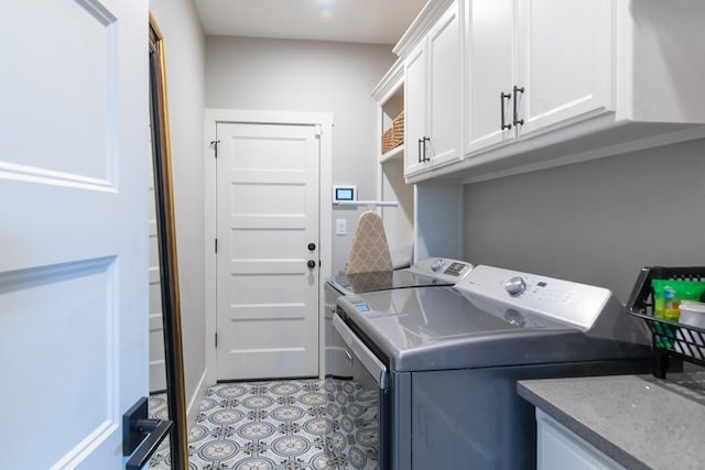 clothes washing area with light tile patterned floors, cabinet space, and washer and dryer