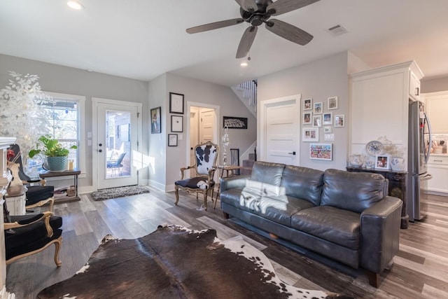 living room with recessed lighting, visible vents, wood finished floors, and stairway