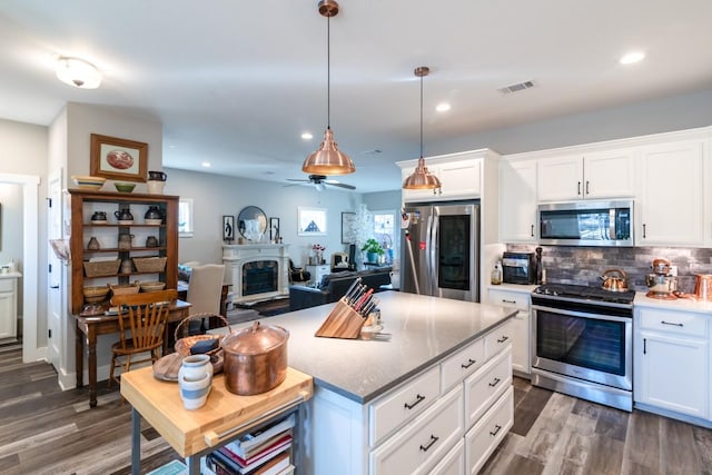 kitchen with a wealth of natural light, decorative backsplash, appliances with stainless steel finishes, and a fireplace