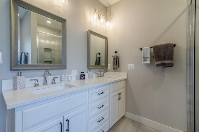 bathroom with double vanity, an enclosed shower, baseboards, and a sink