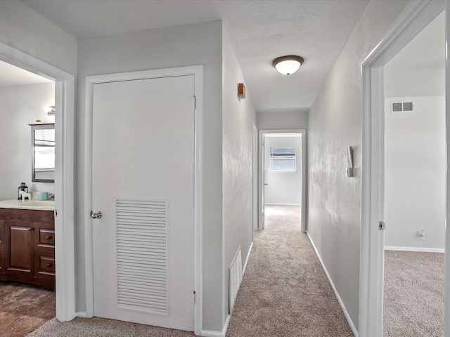 corridor with sink and light colored carpet