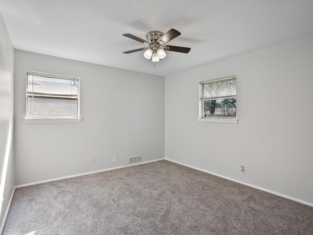 spare room with a wealth of natural light, ceiling fan, and carpet flooring