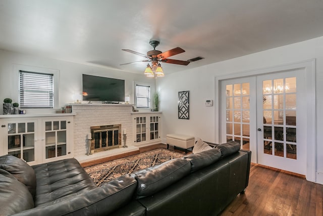 living room with french doors, ceiling fan, dark hardwood / wood-style flooring, and a brick fireplace