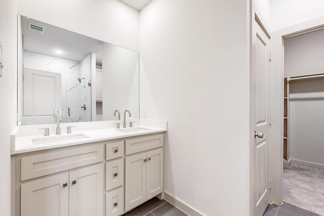 bathroom with visible vents, a sink, a marble finish shower, and double vanity