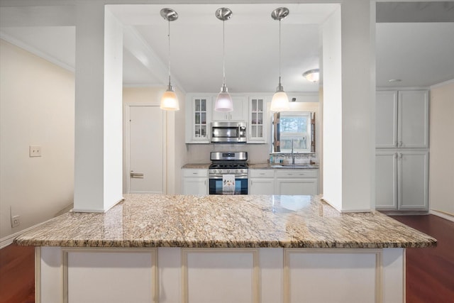 kitchen with pendant lighting, appliances with stainless steel finishes, light stone counters, and white cabinets