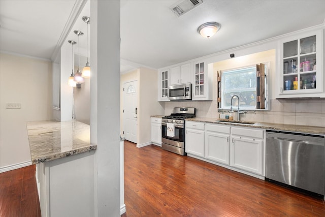 kitchen with stainless steel appliances, white cabinetry, sink, and decorative light fixtures