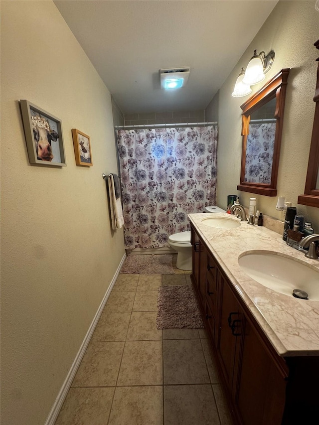 bathroom featuring double vanity, tile patterned flooring, a sink, and toilet