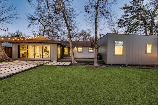 back house at dusk with a lawn