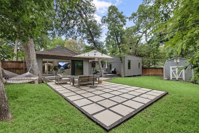 rear view of house with a storage unit, a yard, an outdoor living space, and a patio