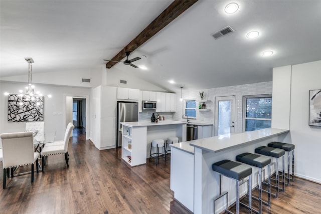 kitchen featuring a breakfast bar, pendant lighting, white cabinetry, kitchen peninsula, and stainless steel appliances