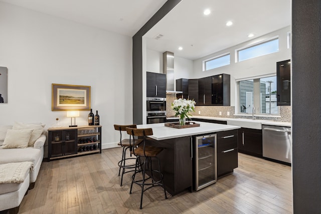 kitchen featuring wine cooler, sink, appliances with stainless steel finishes, a kitchen breakfast bar, and a kitchen island