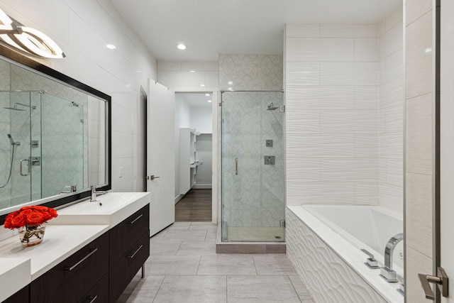 bathroom featuring vanity, shower with separate bathtub, and tile walls