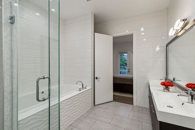 bathroom with vanity, tile patterned floors, independent shower and bath, and tile walls