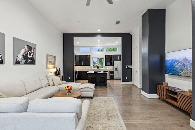 living room with ceiling fan, hardwood / wood-style floors, and a high ceiling