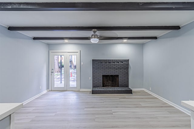 unfurnished living room featuring a brick fireplace, beam ceiling, light hardwood / wood-style floors, and ceiling fan