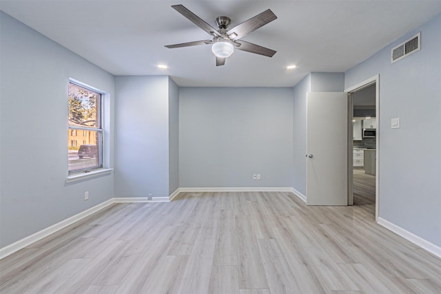 empty room with ceiling fan and light hardwood / wood-style flooring