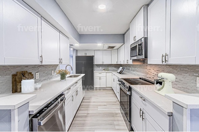 kitchen with sink, white cabinetry, stainless steel appliances, light stone counters, and tasteful backsplash