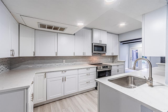 6004 E University Blvd Unit 131, Dallas, TX 75206 - kitchen featuring backsplash, visible vents, a sink, white cabinets, and stainless steel appliances
