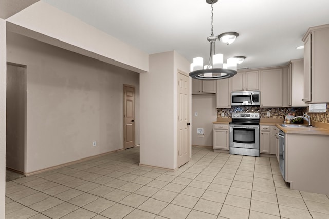 kitchen with sink, a chandelier, hanging light fixtures, appliances with stainless steel finishes, and backsplash