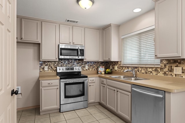 kitchen featuring light tile patterned flooring, appliances with stainless steel finishes, sink, and decorative backsplash