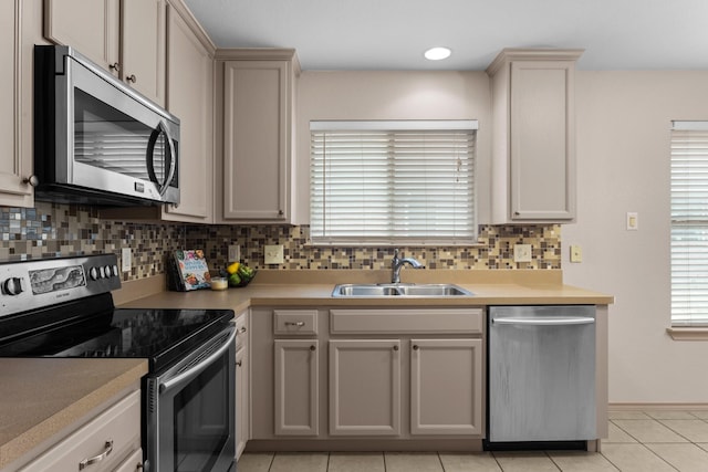 kitchen with tasteful backsplash, sink, light tile patterned floors, and stainless steel appliances