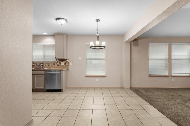 kitchen with light tile patterned floors, hanging light fixtures, tasteful backsplash, a notable chandelier, and stainless steel dishwasher