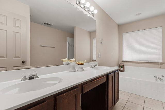 bathroom featuring tile patterned flooring, vanity, and tiled bath