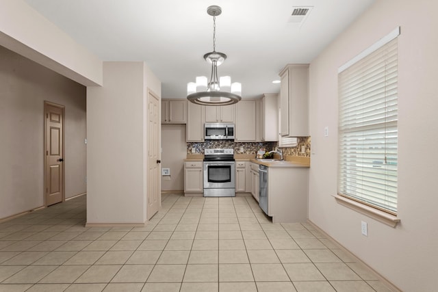 kitchen with decorative backsplash, hanging light fixtures, light tile patterned floors, stainless steel appliances, and an inviting chandelier