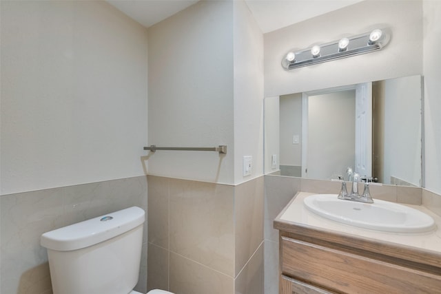 bathroom featuring vanity, tile walls, and toilet