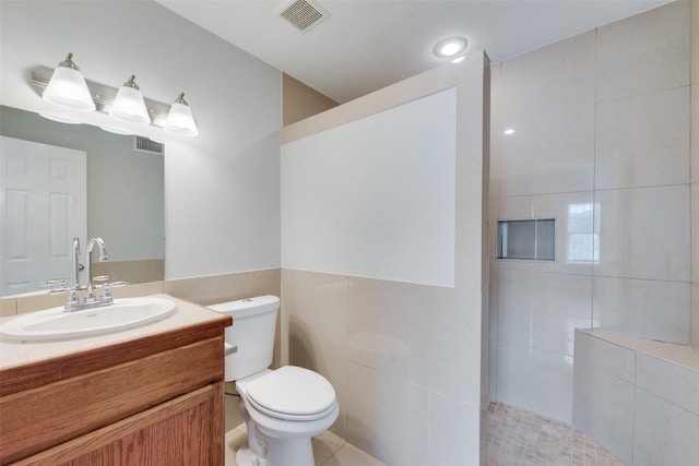 bathroom featuring tile walls, vanity, tile patterned floors, and toilet