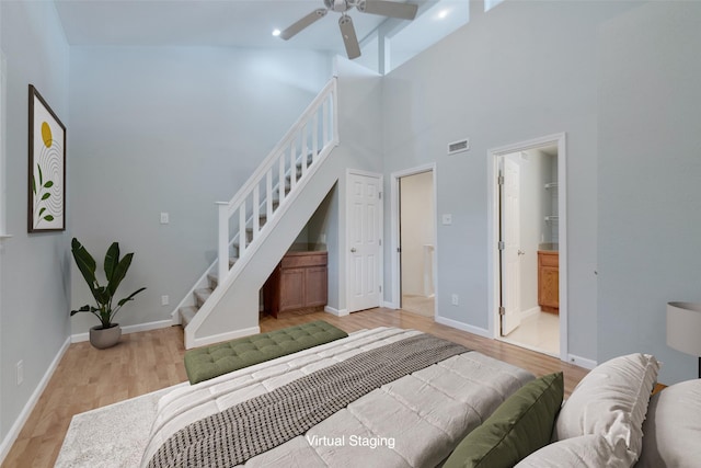 bedroom featuring ensuite bath, light hardwood / wood-style flooring, and a high ceiling