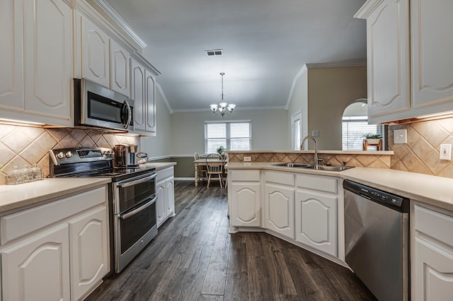 kitchen with appliances with stainless steel finishes, sink, white cabinets, hanging light fixtures, and ornamental molding