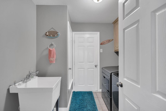 laundry area with cabinets, washer and dryer, sink, and light tile patterned floors